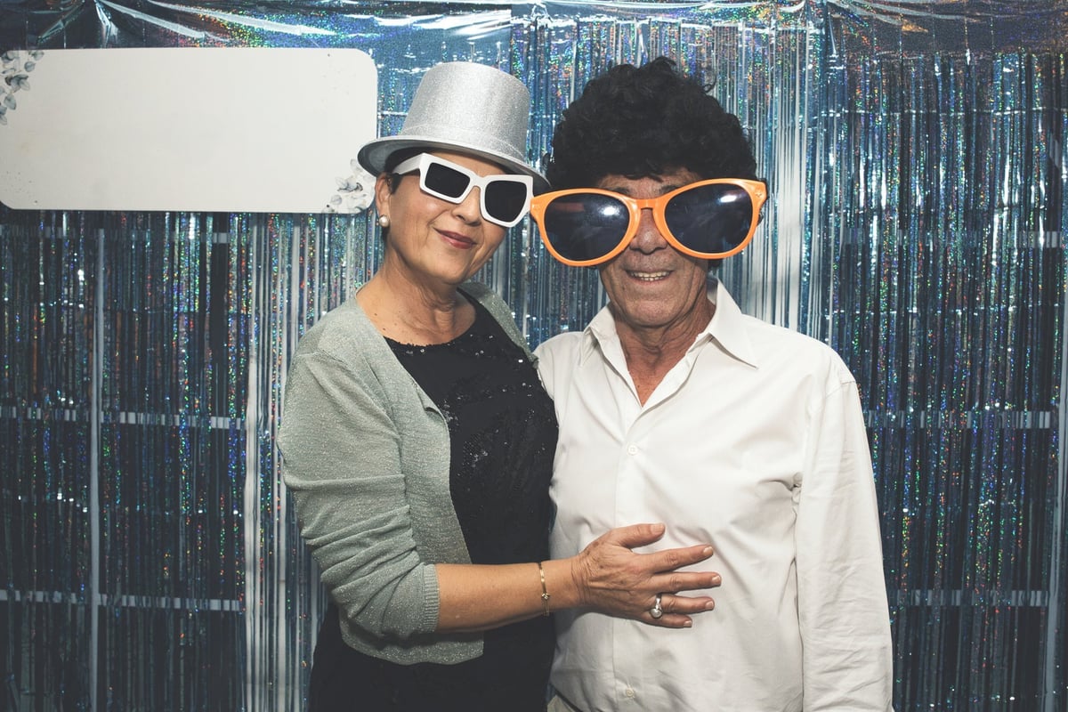 Senior couple wearing oversized glasses, posing together for a photo booth